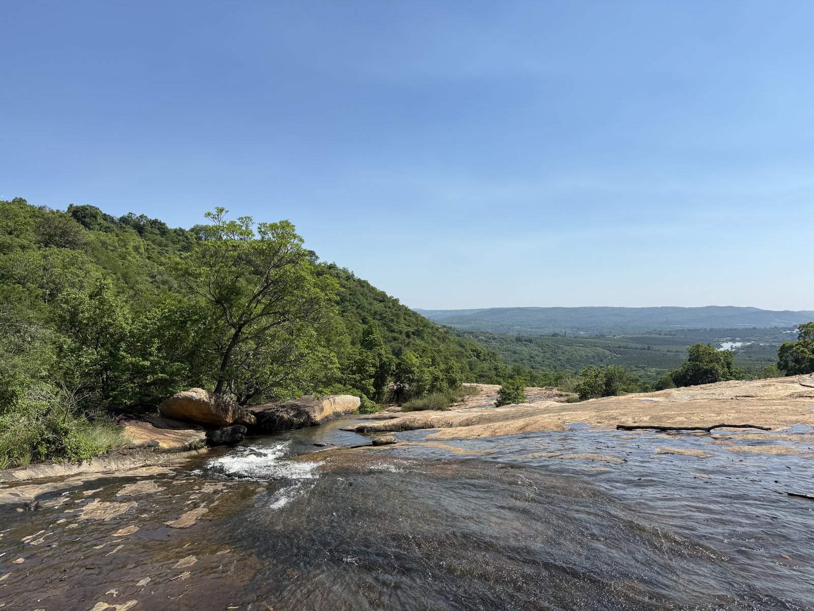 The Lowveld around Kanaan — smooth rock outcrops giving way to valley forest and farmland rolling toward the escarpment, a natural place for slow walks.