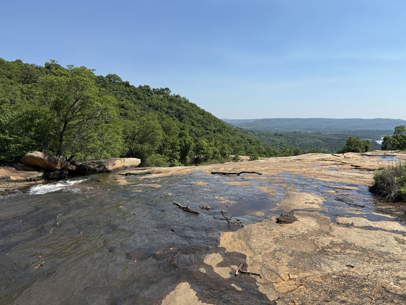 The waterfall on Kanaan, with the Lowveld valley running on toward the Kruger gates — the land the journey begins from.